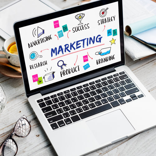 Laptop displaying digital marketing concepts like strategy, branding, advertising, and research on a workspace.